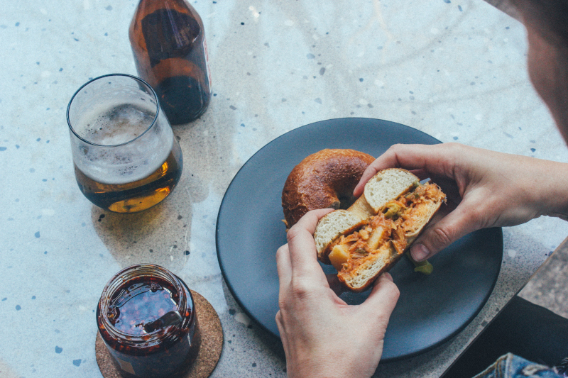 Manos tomando un bagle partido por la mitad